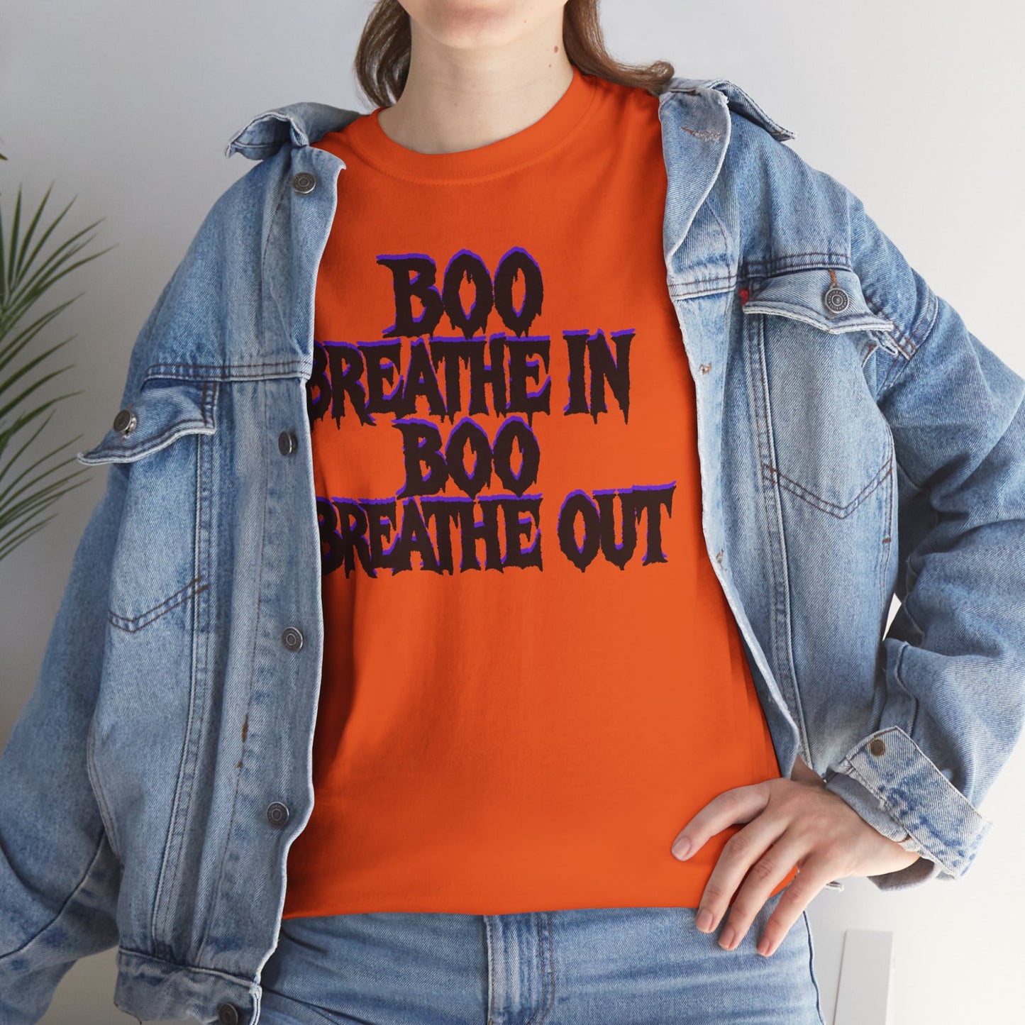 Person wearing an orange t-shirt with 'BOO BREATHE IN BOO BREATHE OUT' text, paired with a denim jacket.